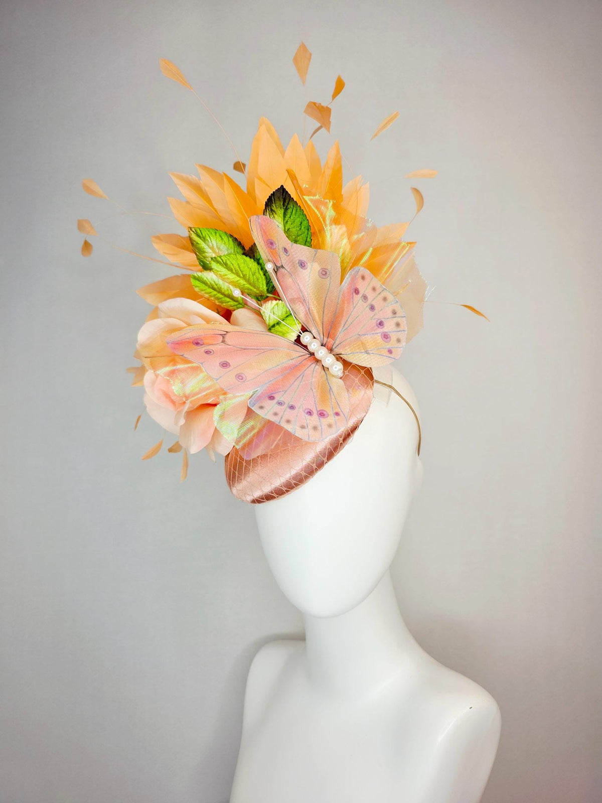 kentucky derby hat fascinator champagne pink satin with netting light pink satin rose green leaves burnt orange feathers and large butterfly