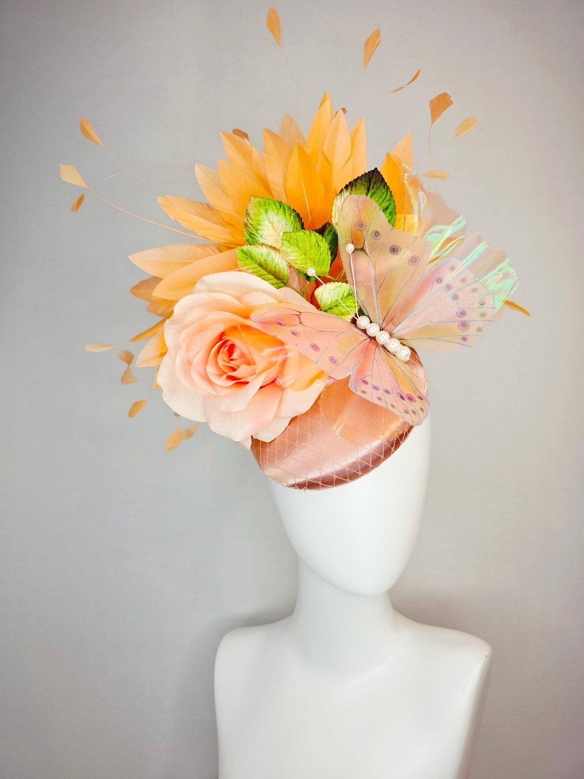 kentucky derby hat fascinator champagne pink satin with netting light pink satin rose green leaves burnt orange feathers and large butterfly