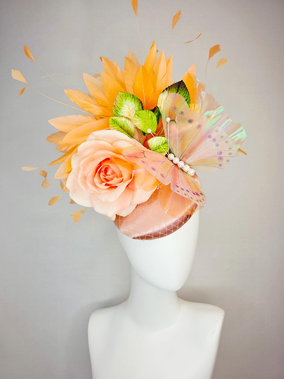 kentucky derby hat fascinator champagne pink satin with netting light pink satin rose green leaves burnt orange feathers and large butterfly