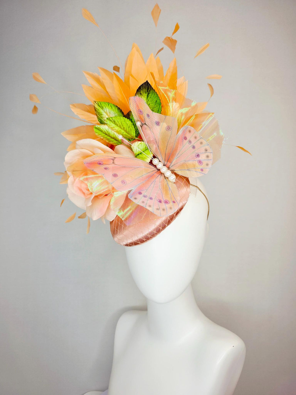 kentucky derby hat fascinator champagne pink satin with netting light pink satin rose green leaves burnt orange feathers and large butterfly