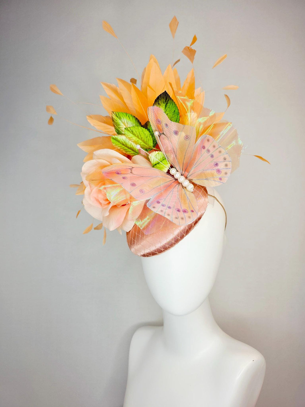 kentucky derby hat fascinator champagne pink satin with netting light pink satin rose green leaves burnt orange feathers and large butterfly