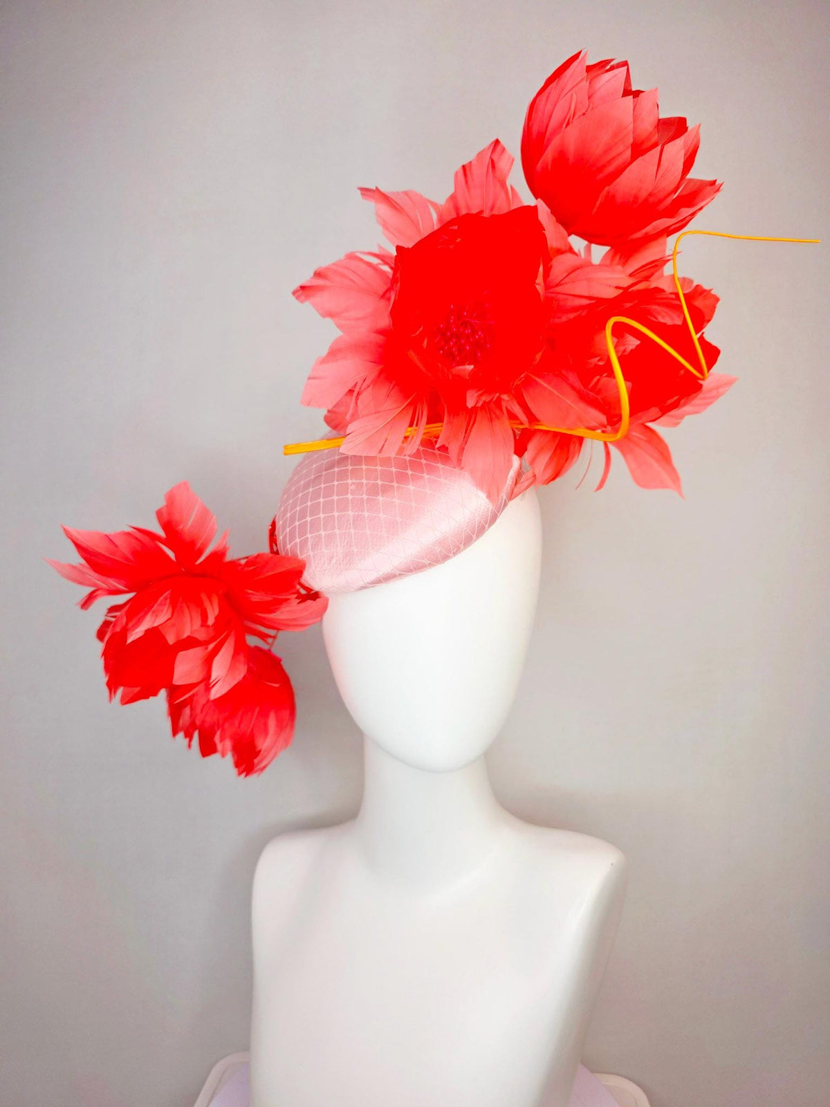 kentucky derby hat fascinator light pink satin with netting and large fluffy coral red feather flowers and light peach orange feathers